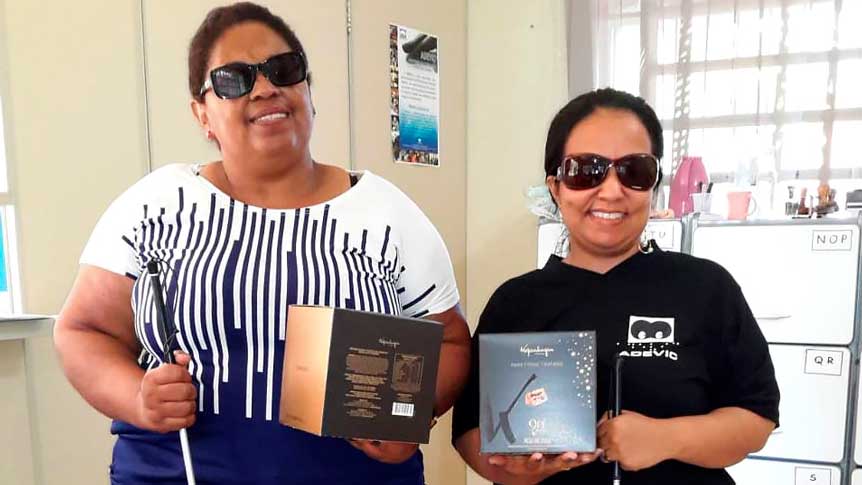 Duas mulheres sorriem segurando cada uma sua caixa de panetone
